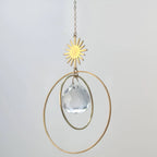 Attrape-soleil en cristal avec connecteur étoile en laiton, anneaux dorés et prisme en cristal de verre, suspendu à une chaîne délicate.
