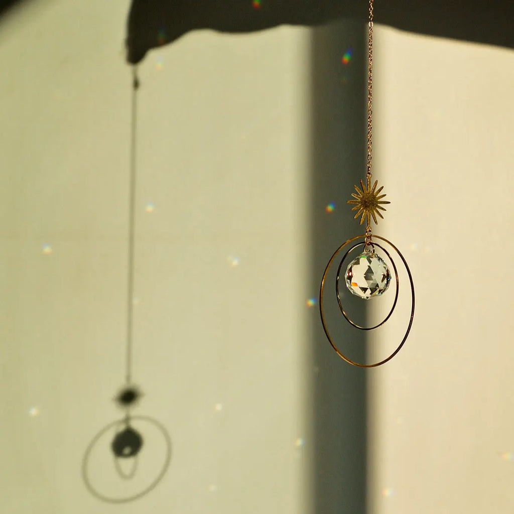 Attrape lumière Galaxy en laiton avec cristal de verre, créant des reflets lumineux sur un mur.