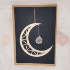 Attrape-soleil Lune en contreplaqué découpé au laser en forme de lune avec prisme en cristal sur fond noir.