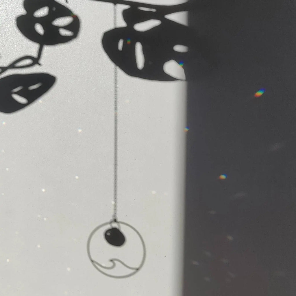 Mini attrape soleil Wave avec pendentif vague en laiton projetant une ombre, améliorant la tranquillité intérieure et l'énergie positive.