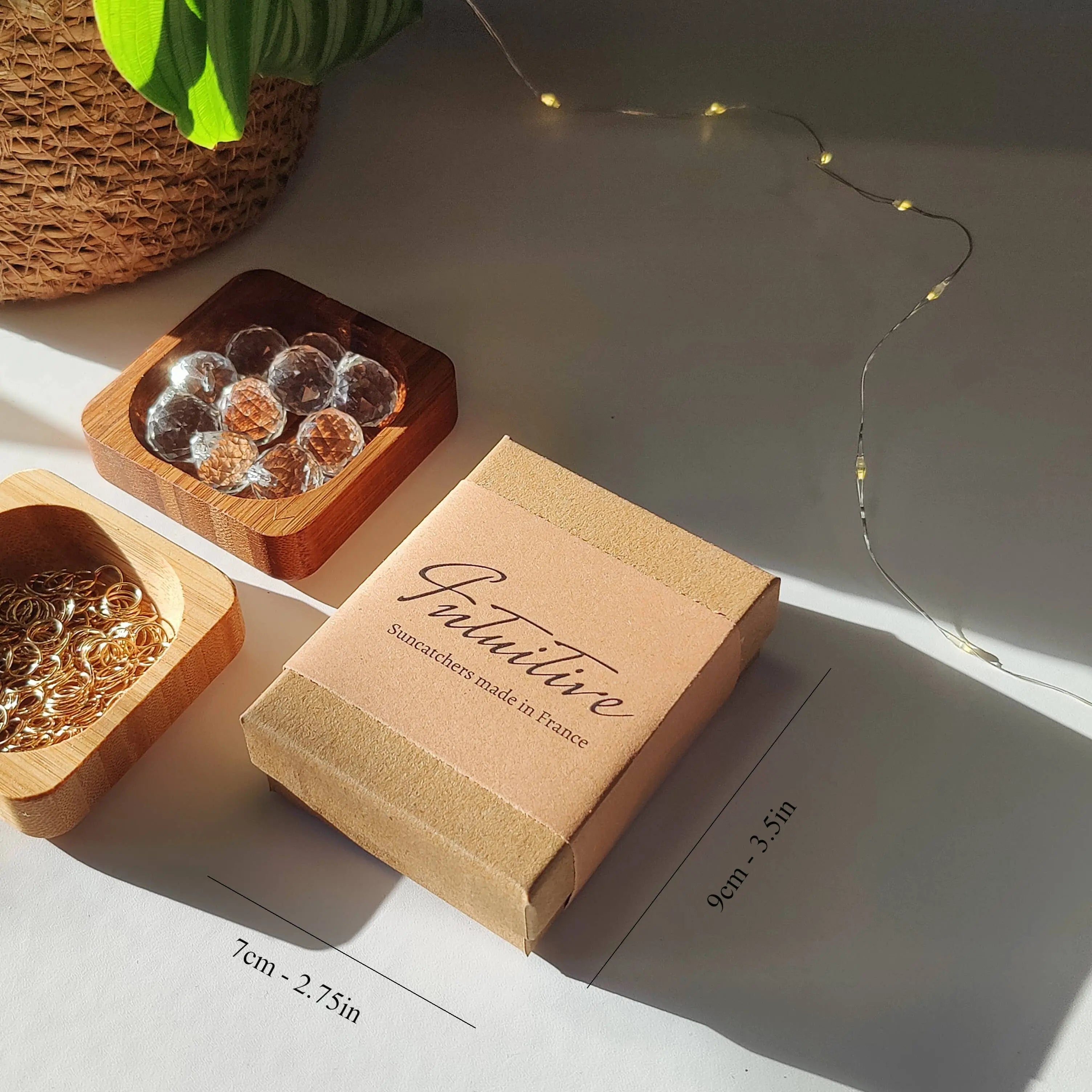 Coffret cadeau écologique avec plantes naturelles et plateaux en bois exposés au soleil, avec anneaux dorés et éléments transparents.
