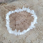 Bracelet en pierre de lune blanc sur une surface texturée de sable.