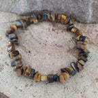 Bracelet en pierres naturelles doeil du tigre exposé sur une surface de cristal et de bois.