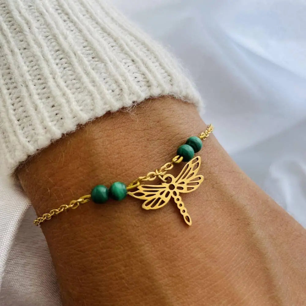 Bracelet charm libellule en or avec pierres naturelles vertes, élégant et raffiné sur poignet.