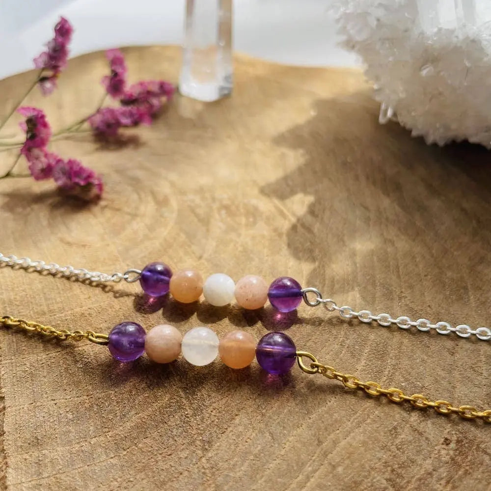 Bracelet Positivité en améthyste, pierre de lune et pierre du soleil sur une surface en bois naturel.