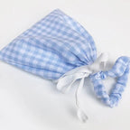 Sachet en tissu vichy bleu avec un élastique assorti, parfait pour le rangement ou un cadeau.