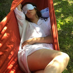 Femme se relaxant dans un hamac avec un masque pour les yeux, profitant d'un moment de détente en plein air.