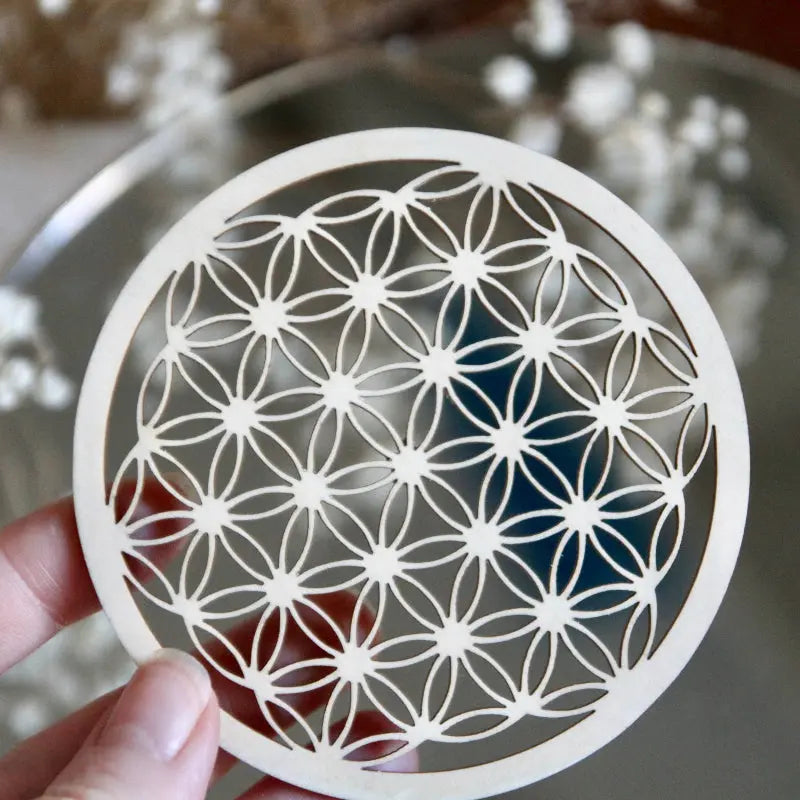 Fleur de vie en bois avec pierres, utilisée pour recharger vos pierres et purifier les objets spirituels, sur une surface en bois.