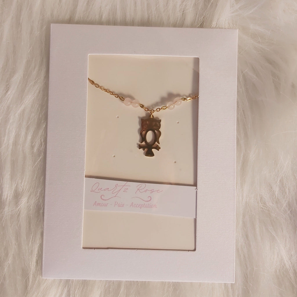 Bracelet Charme hibou doré sur fond de carte blanche avec texture de fourrure douce.