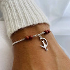 Bracelet Chat en pierre naturelle avec pendentif en forme de chat et perles rouges, porté sur un poignet.